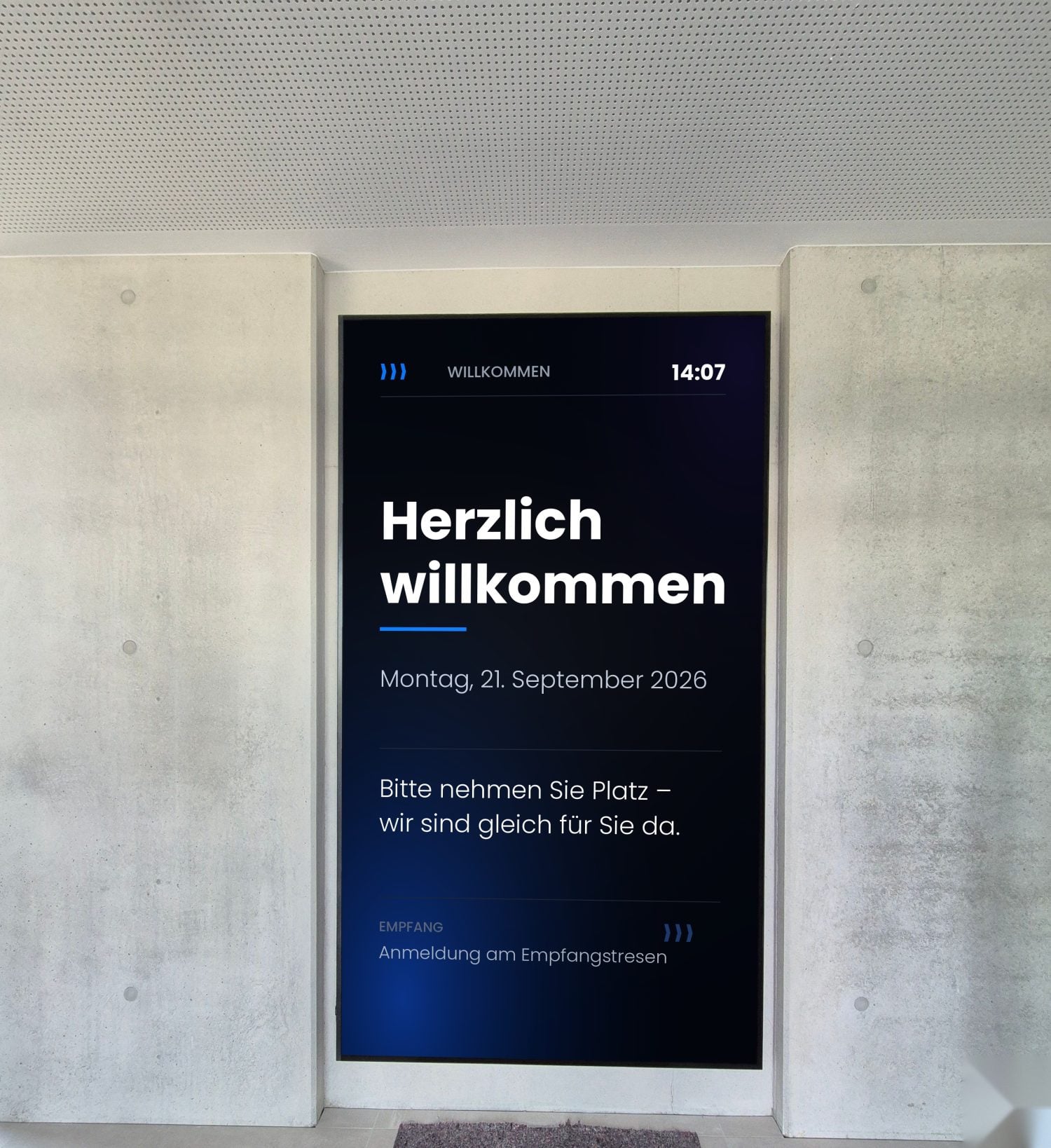 Samsung QH115FX im Hochformat in einer Sichtbetonnische im Eingangsbereich