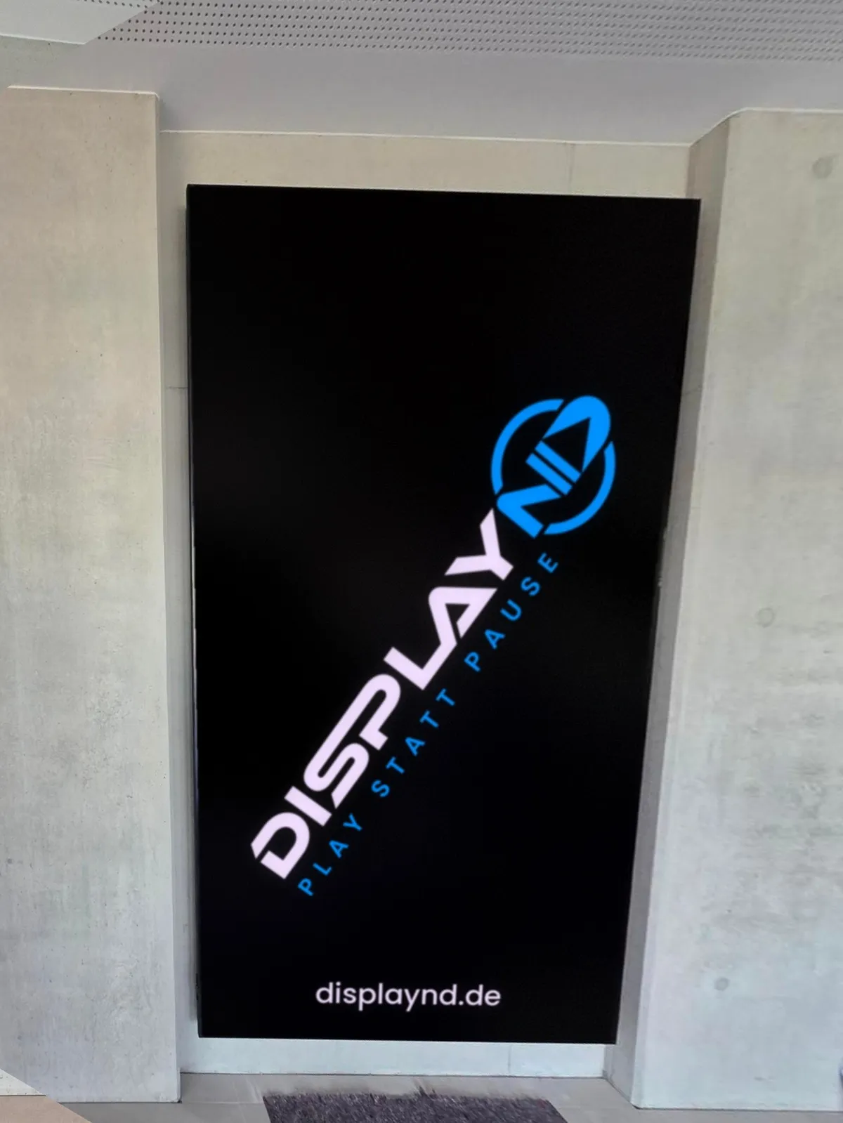Nach der Montage: 115-Zoll-Display im Hochformat in einer Betonnische am Empfang